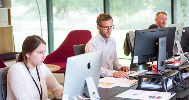 Group of professionals working on computers in a modern office environment.